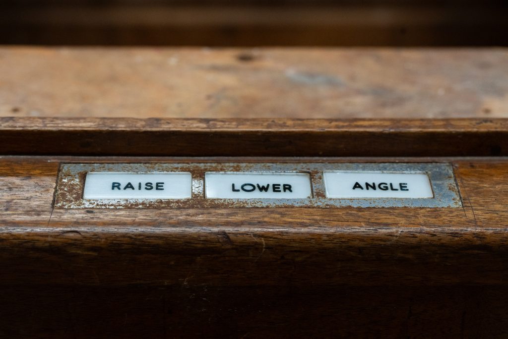 The buttons that were used to raise and lower the lectern’s inner mechanism to the speaker’s preferred height. Due to missing portions of the mechanism, this function is no longer usable and obscures part of the original lectern height set by President Kennedy. / Photograph by Aaron Rodriguez